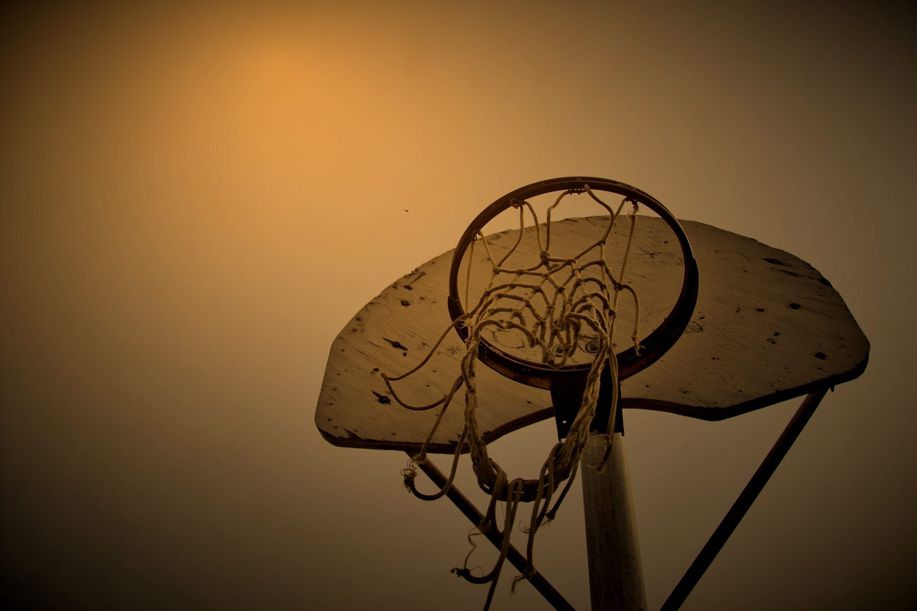 Bare outdoor hoop and backboard on a grey evening