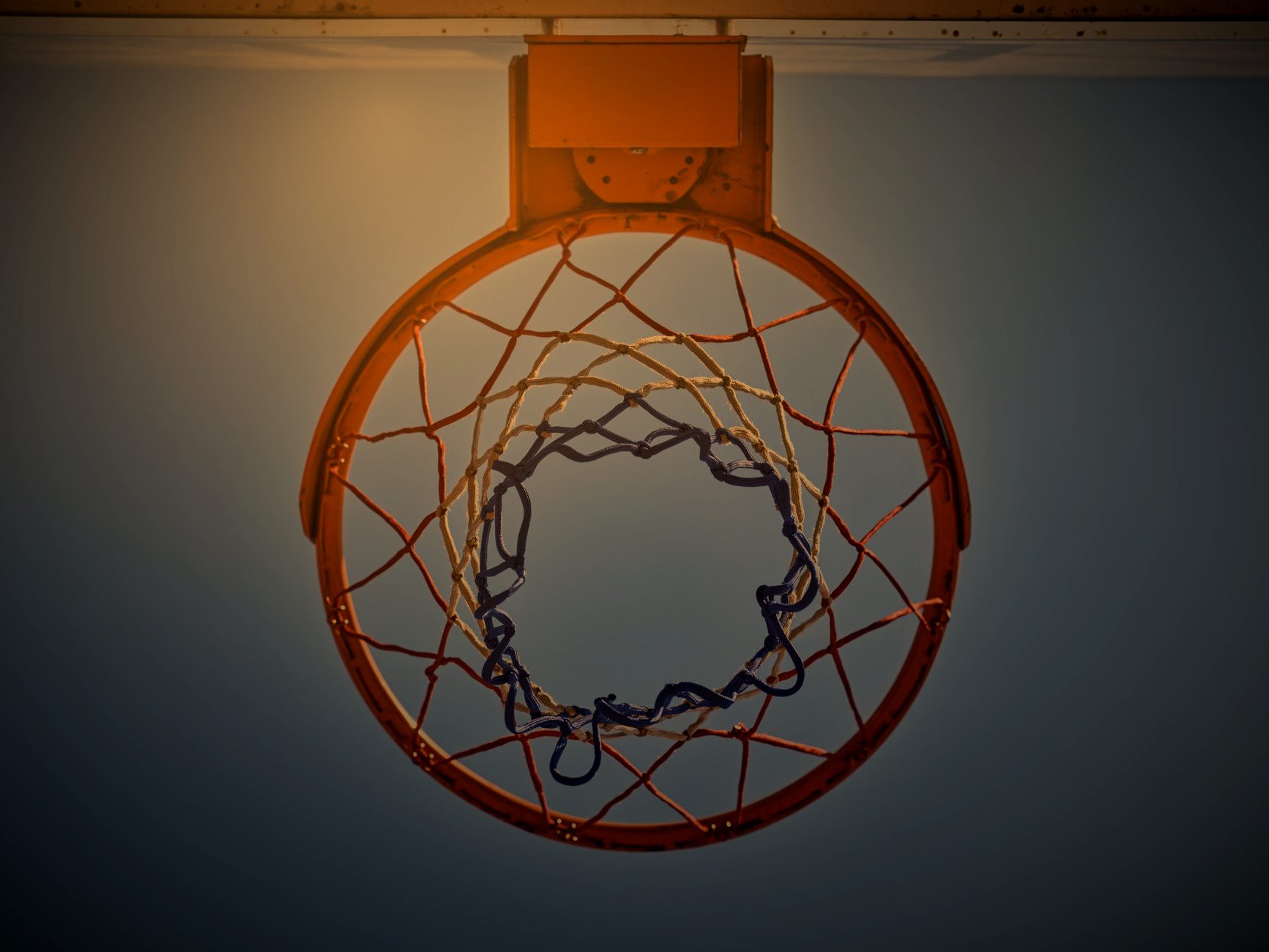 Basketball rim and net seen from below against the sky
