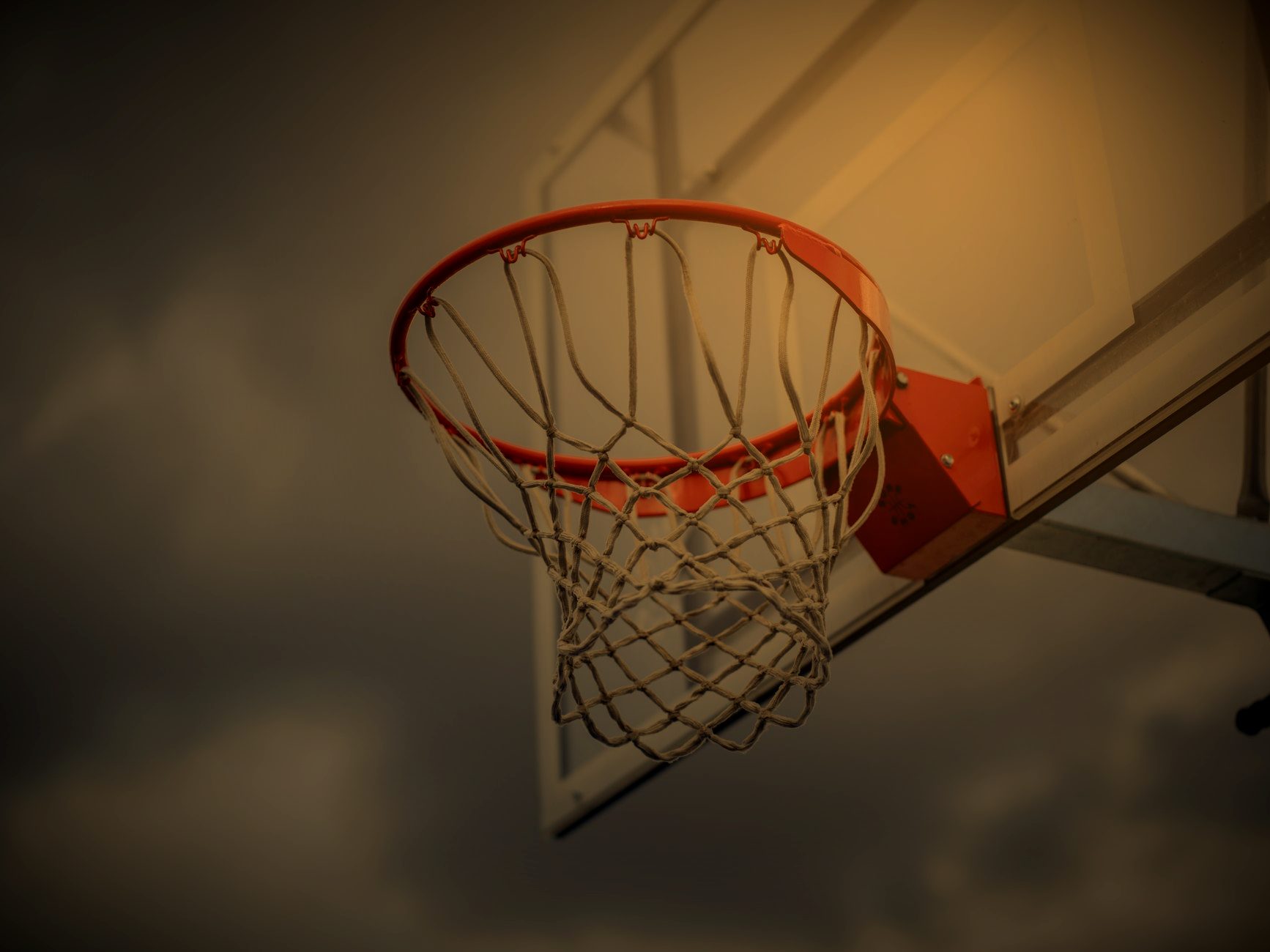 Basketball rim and backboard against an overcast sky
