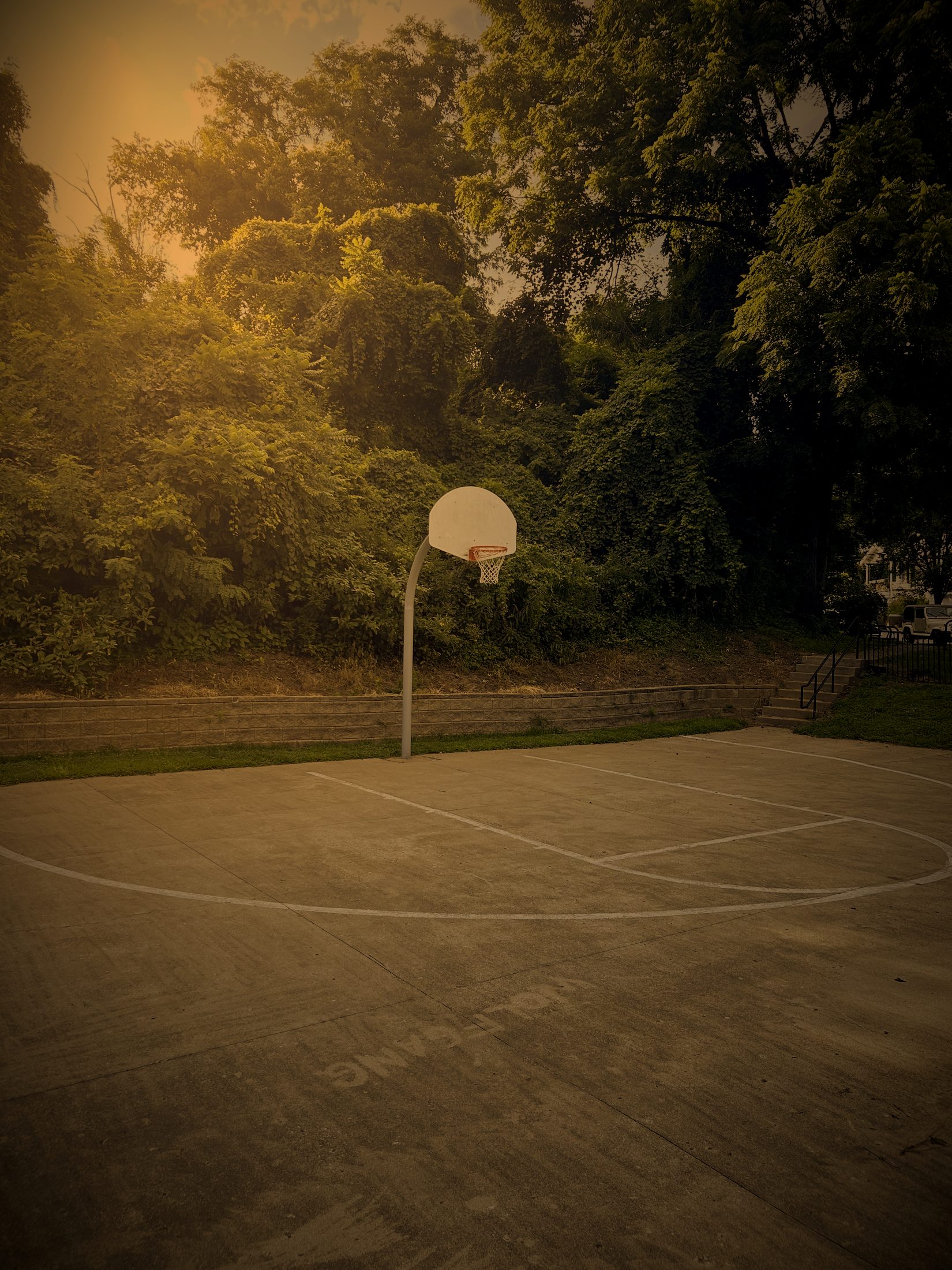 Hoop above a concrete court backed by a stone retaining wall at Swope
